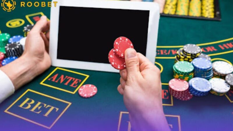 An image of a person on a gaming table with playing chips and a tablet